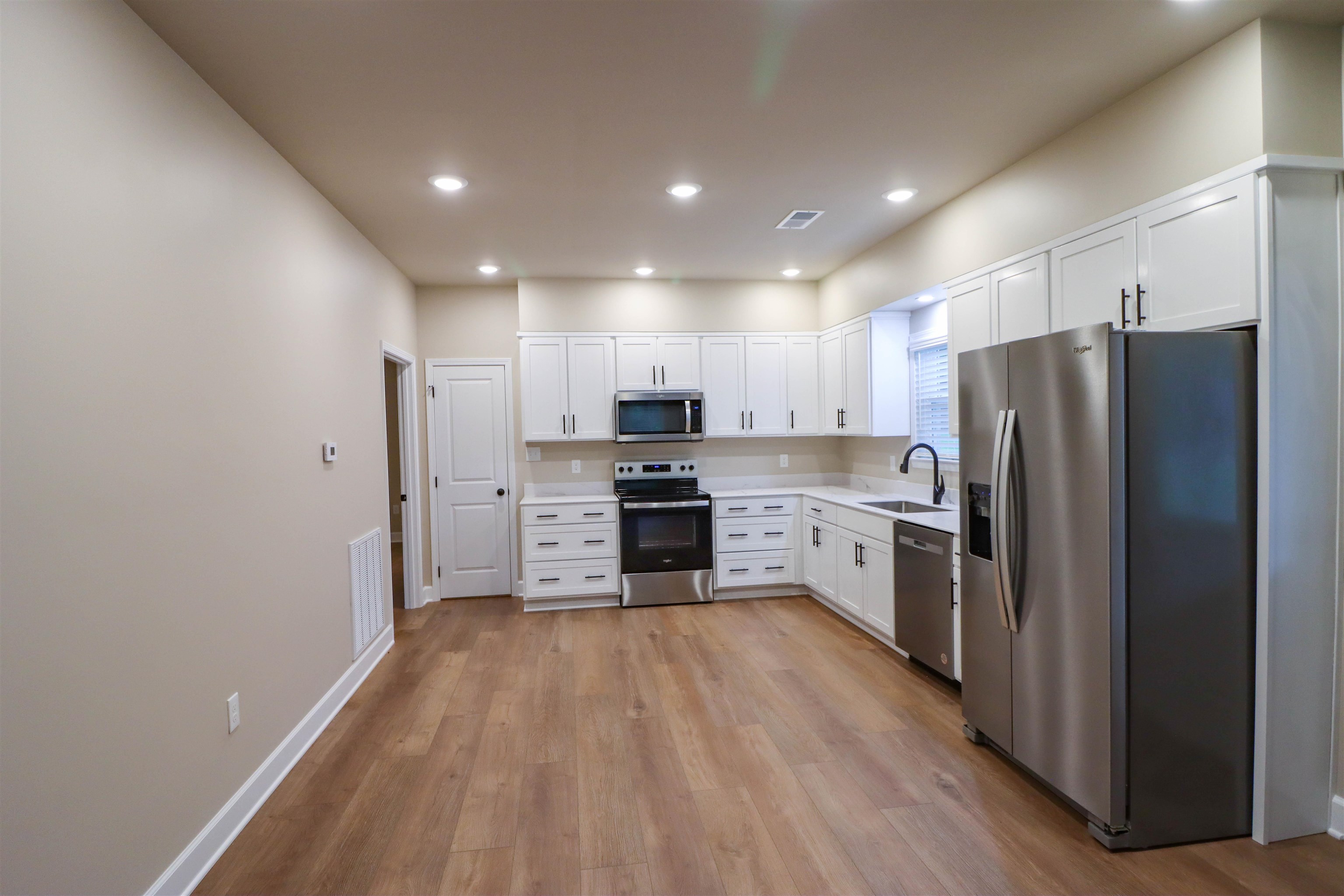 208 Church Street Ripley, TN 38063 - Photo 8 of 33 Kitchen with stainless steel appliances, a sink, light countertops, luxury vinyl floors, and white cabinet