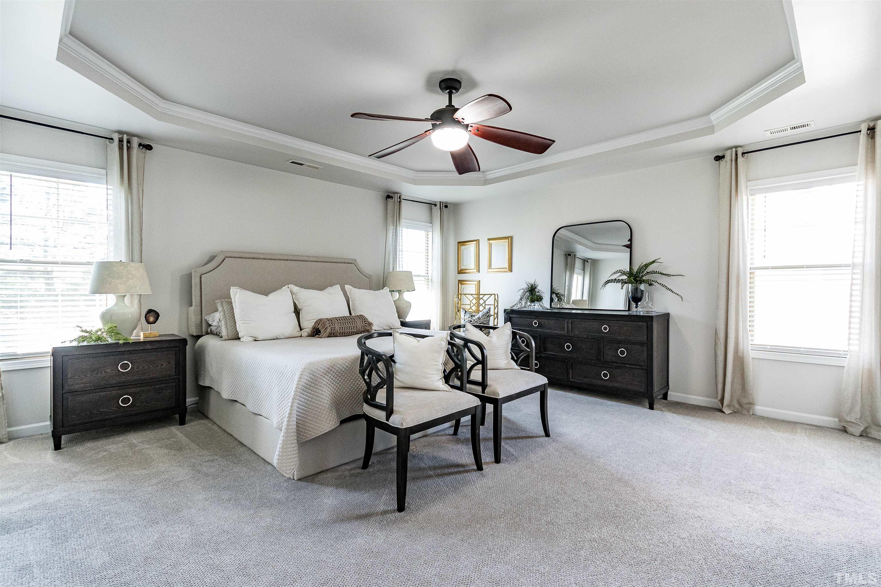 9009 Cornwell Drive Wake Forest, NC 27587 - Photo 24 of 36 a spacious bedroom with a bed and a chandelier