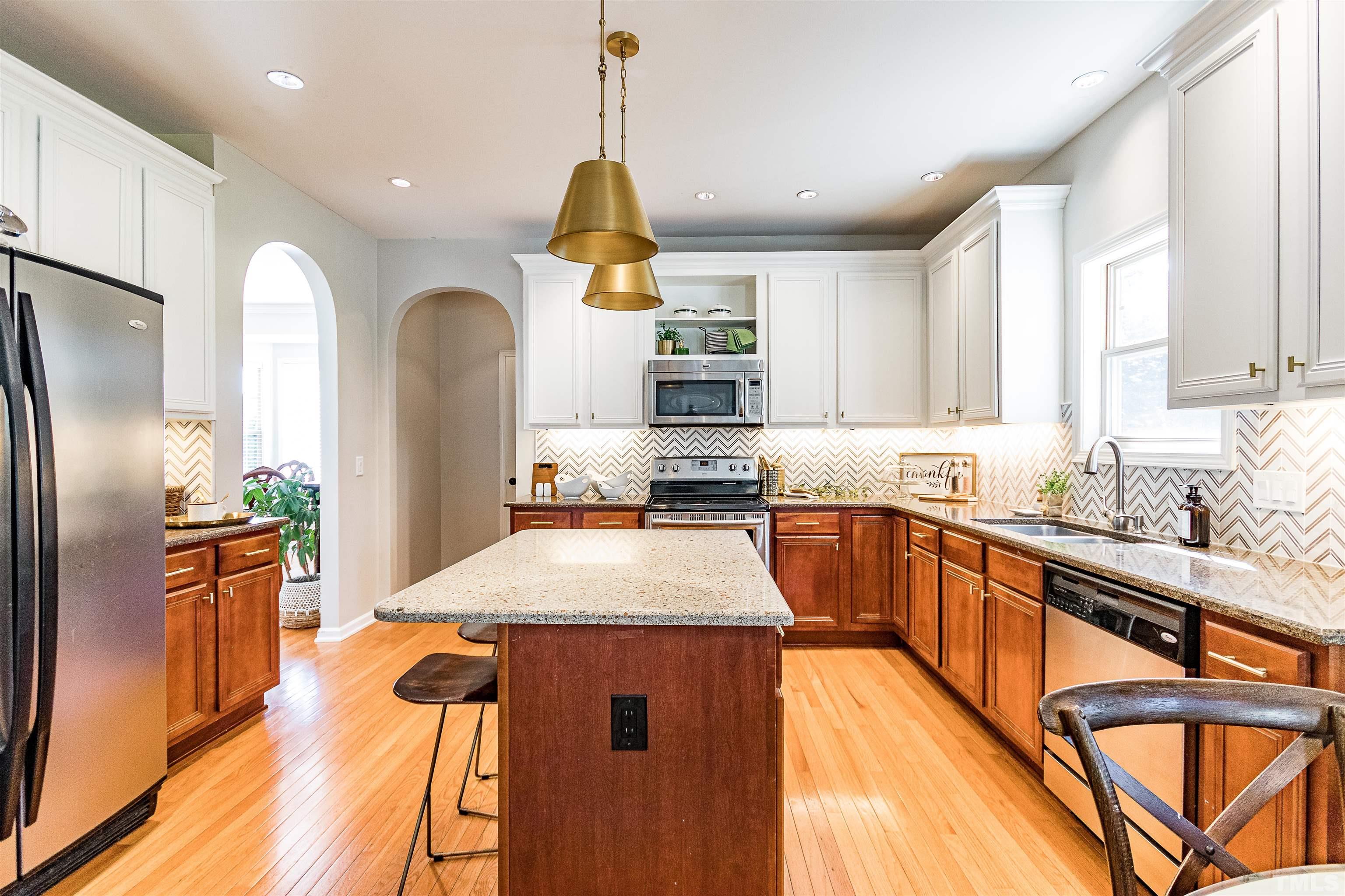 9009 Cornwell Drive Wake Forest, NC 27587 - Photo 9 of 36 a kitchen with stainless steel appliances kitchen island granite countertop a refrigerator a sink dishwasher a stove and a dining table with wooden floor