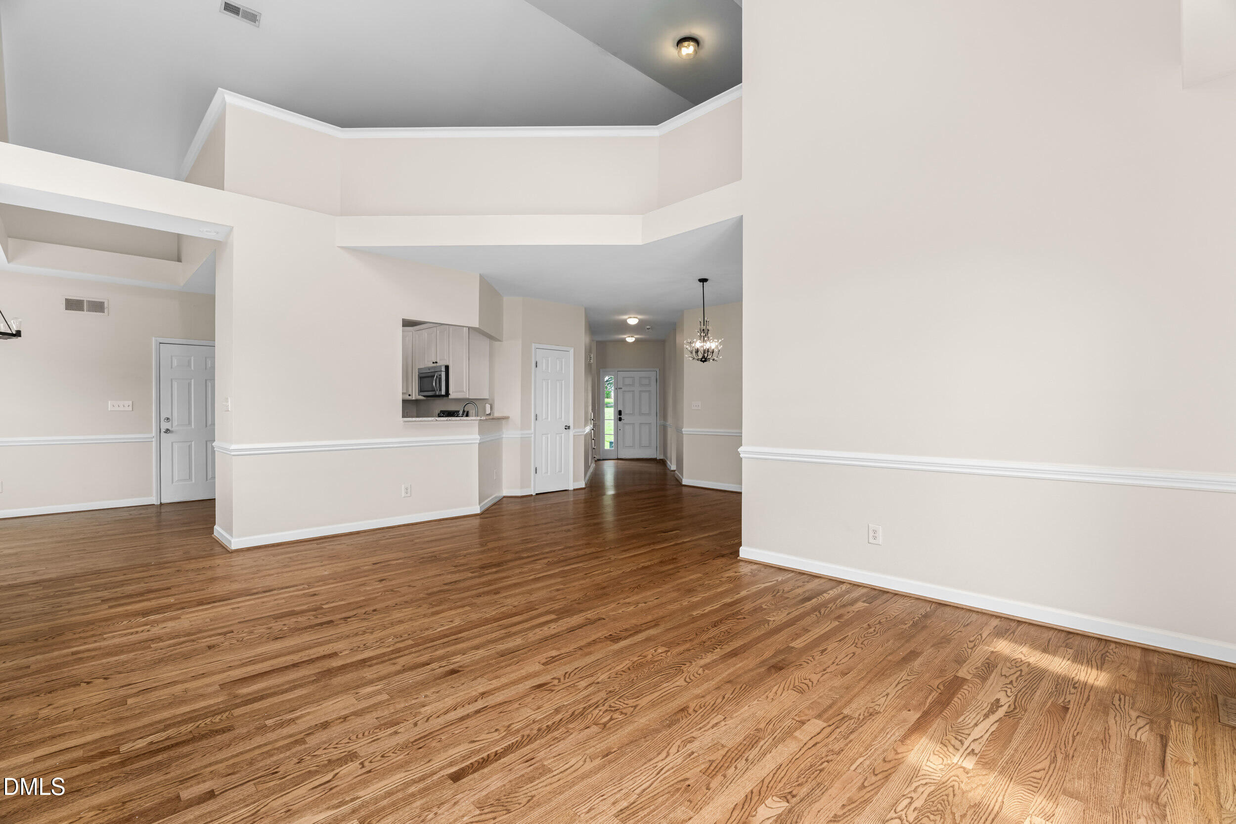 744 Seastone Street Raleigh, NC 27603 - Photo 18 of 53 a view of an empty room with wooden floor and a kitchen