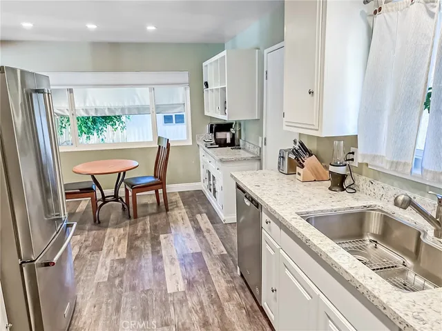 a kitchen with stainless steel appliances granite countertop a refrigerator a sink a stove and white cabinets