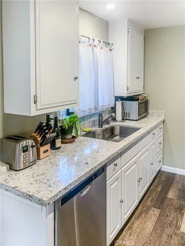 a kitchen with granite countertop a sink and a white cabinets