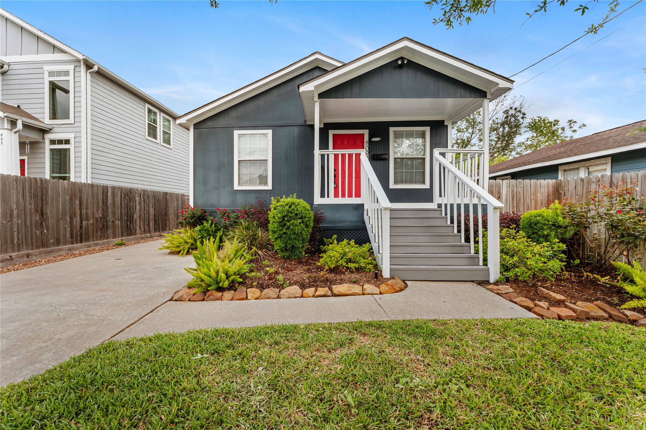 809 East 40th Street Houston, TX 77022 - Photo 3 of 13 Inviting front porch with classic railing detail and a bold red front door that adds character and charm. Thoughtfully landscaped beds enhance the welcoming feel of the home. Solar system includes an 11.5 kWh panel array paired with a 13 kWh Tesla Powerwall for reliable energy storage.