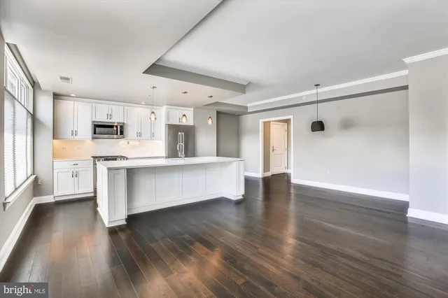 a large white kitchen with wooden floors and view living room