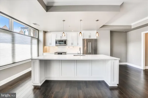 a kitchen with stainless steel appliances a sink a stove a refrigerator and wooden floor