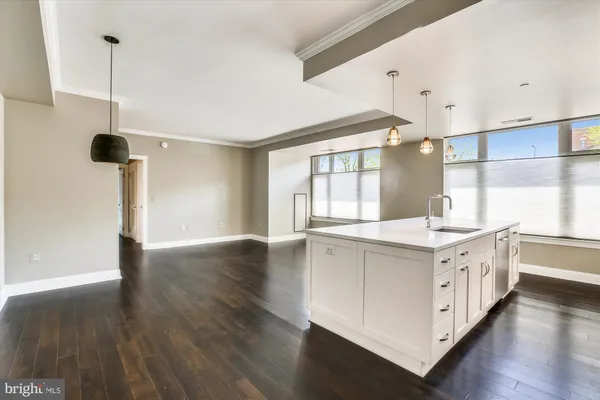 a large white kitchen with wooden floors and view living room