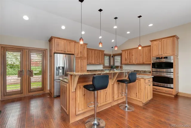 a kitchen with stainless steel appliances granite countertop a stove a refrigerator a sink a kitchen island a dining table and chairs