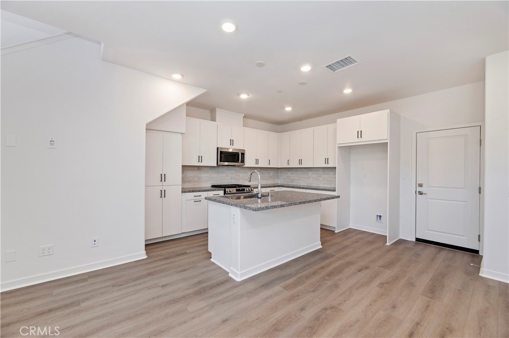 3975 Lavine Way Corona, CA 92883 - Photo 8 of 24 a kitchen with stainless steel appliances a sink stove and wooden floor