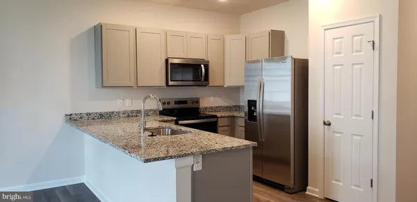 a kitchen with stainless steel appliances granite countertop a refrigerator a stove microwave and sink