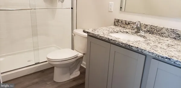 a bathroom with a granite countertop sink a toilet and shower
