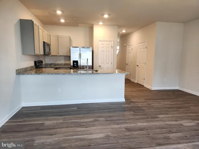 a view of a kitchen with kitchen island a sink wooden floor and a counter top space