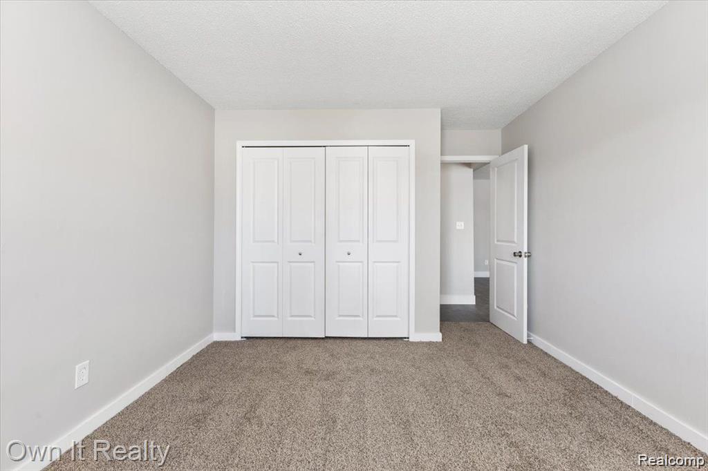 59314 Van Dyke Road Washington, MI 48094 - Photo 9 of 16 Unfurnished bedroom with carpet flooring, a textured ceiling, and a closet