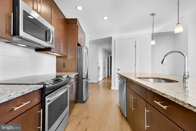 a kitchen with stainless steel appliances granite countertop a stove a sink and a microwave