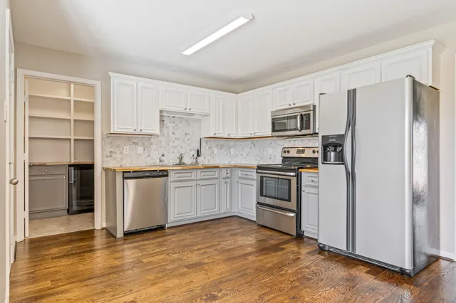 a kitchen with granite countertop a refrigerator and a stove top oven