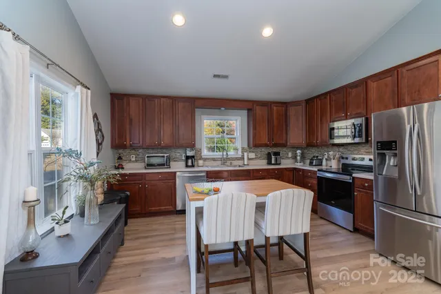 a large kitchen with stainless steel appliances wooden floors and wooden cabinets