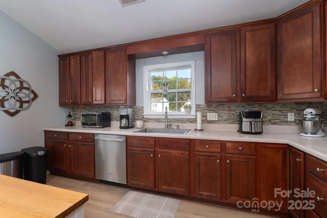 a kitchen with stainless steel appliances granite countertop wooden cabinets a sink and dishwasher with wooden floor