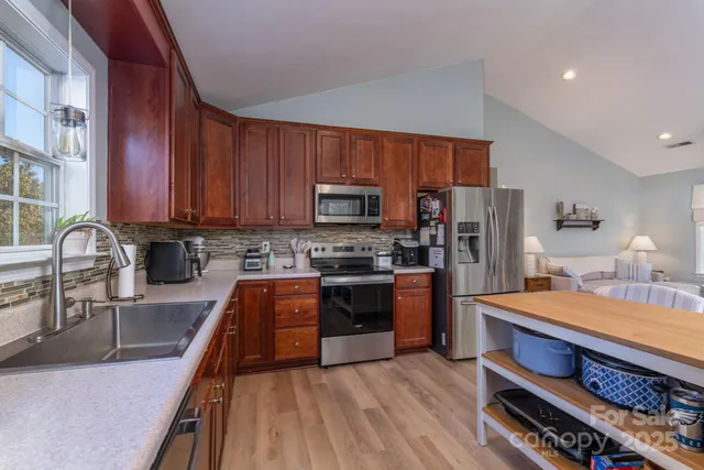 a large kitchen with stainless steel appliances granite countertop a stove a sink dishwasher a microwave oven with cabinets and wooden floor