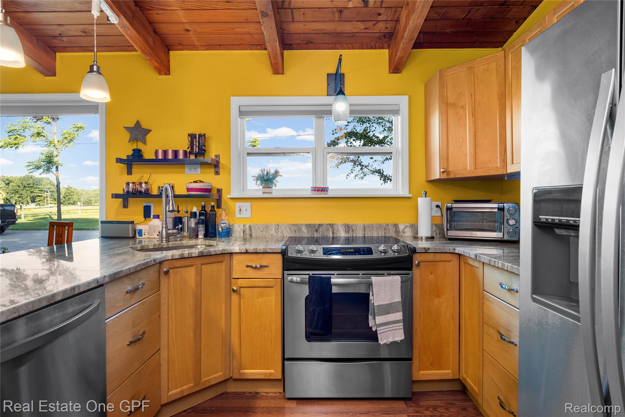 5068 Atkins Road North Street, MI 48049 - Photo 12 of 78 Kitchen featuring light wood cabinetry, stainless steel appliances, speckled stone countertops, a stainless steel sink with a gooseneck faucet, and a wood-beamed ceiling