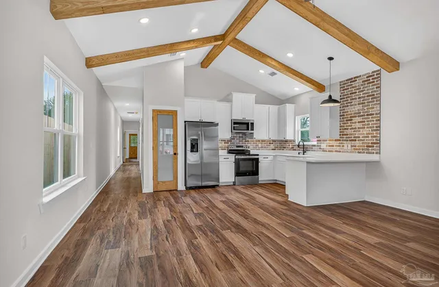 a kitchen with stainless steel appliances granite countertop a refrigerator a sink dishwasher a stove and a microwave oven with wooden floor