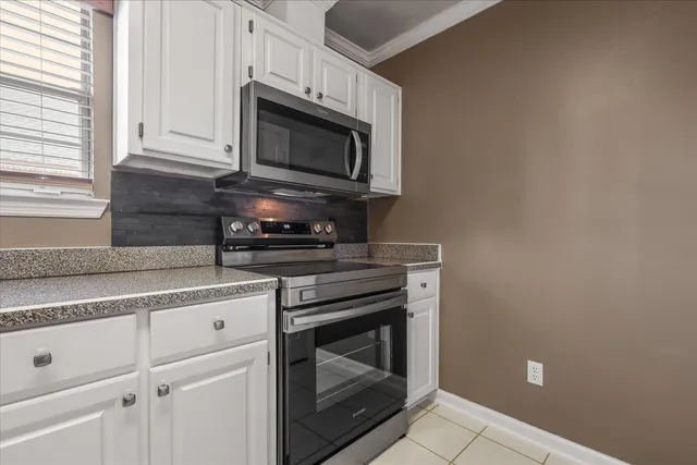 a kitchen with granite countertop white cabinets stainless steel appliances and a window
