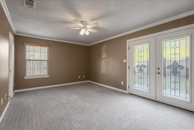an empty room with chandelier fan and windows