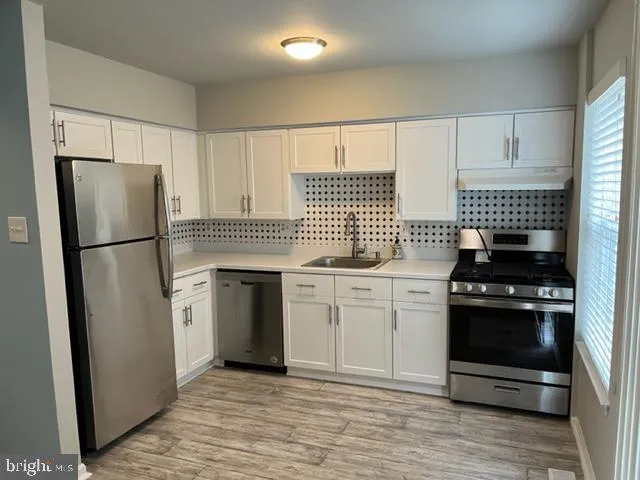 a kitchen with white cabinets and stainless steel appliances