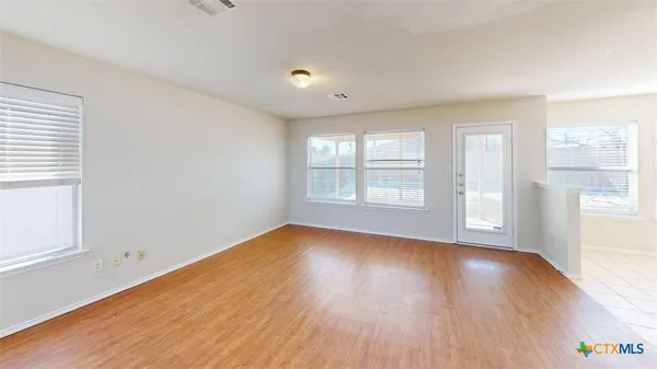 an empty room with wooden floor and windows