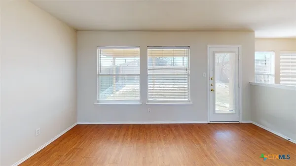 an empty room with wooden floor and windows