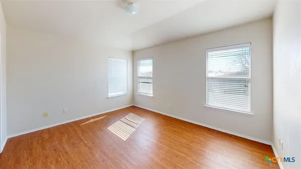 an empty room with wooden floor and windows