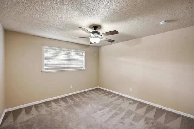 an empty room with windows and ceiling fan