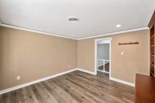 a view of an empty room with wooden floor and closet