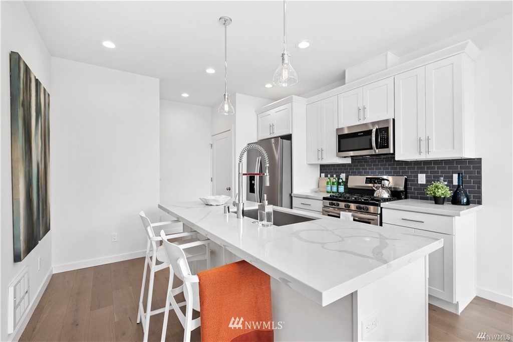 716 North Allen Place Seattle, WA 98103 - Photo 3 of 5 a kitchen with a sink a microwave a stove and chairs