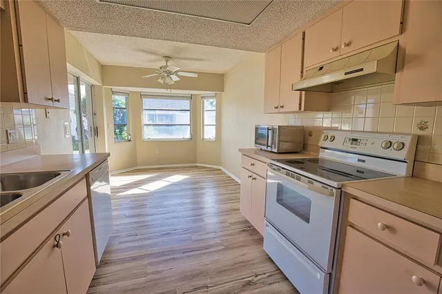 a kitchen with a stove a sink and wooden floor