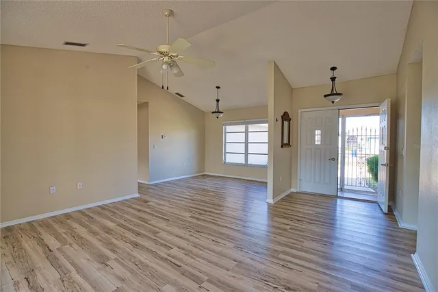 a view of an empty room with wooden floor and a window