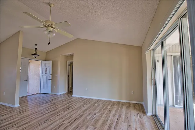 a view of a hallway with wooden floor and a chandelier fan
