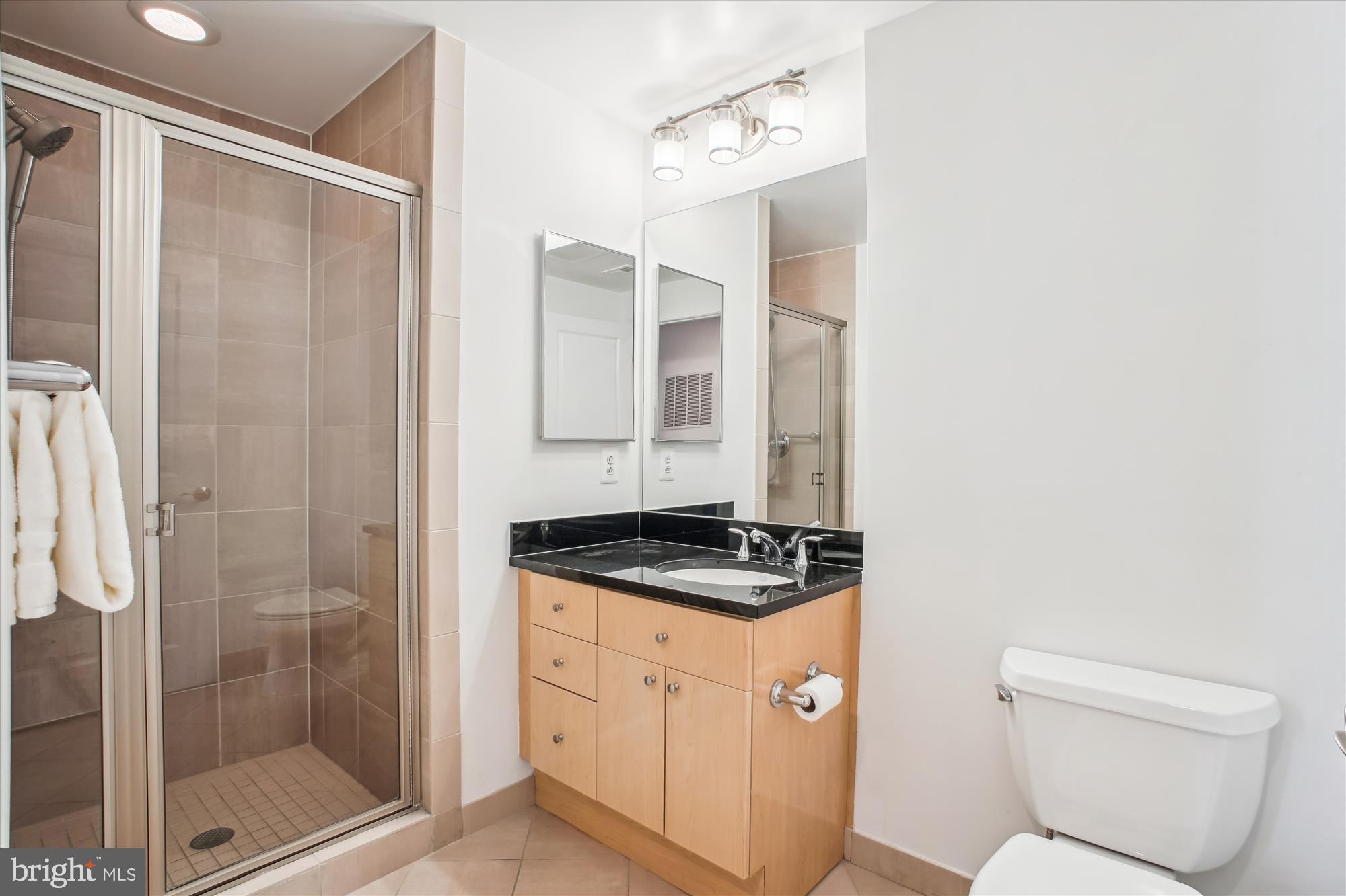 11990 Market Street, Unit 805 Reston, VA 20190 - Photo 30 of 53 a bathroom with a granite countertop sink a toilet a mirror and shower