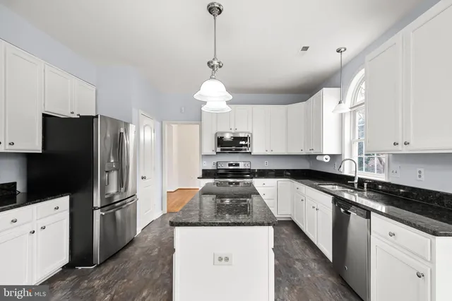 a kitchen with stainless steel appliances granite countertop a sink a stove a refrigerator a center island and cabinets