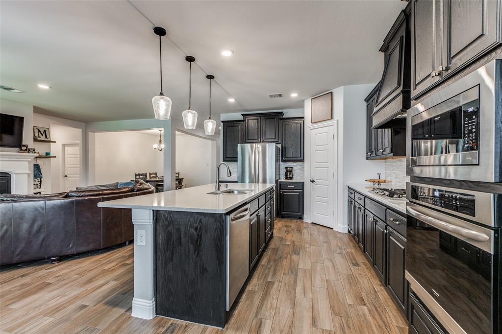 a kitchen with stainless steel appliances granite countertop a kitchen island a stove a sink and a refrigerator