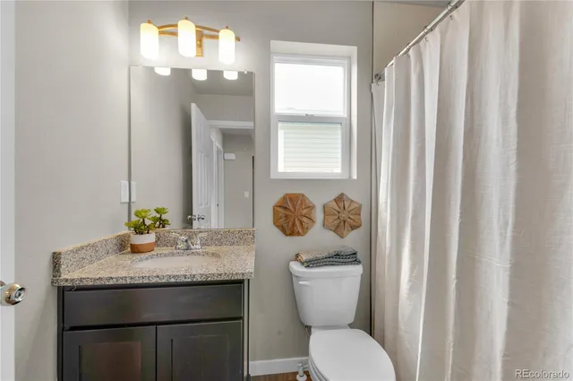 a bathroom with a granite countertop toilet sink and mirror