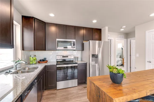 a kitchen with stainless steel appliances kitchen island granite countertop a sink a stove a refrigerator and a refrigerator