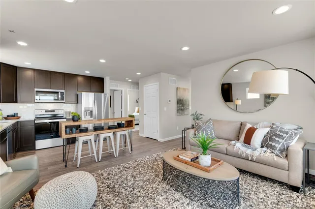 a living room with stainless steel appliances kitchen island granite countertop a couch a stove a dining table and chairs