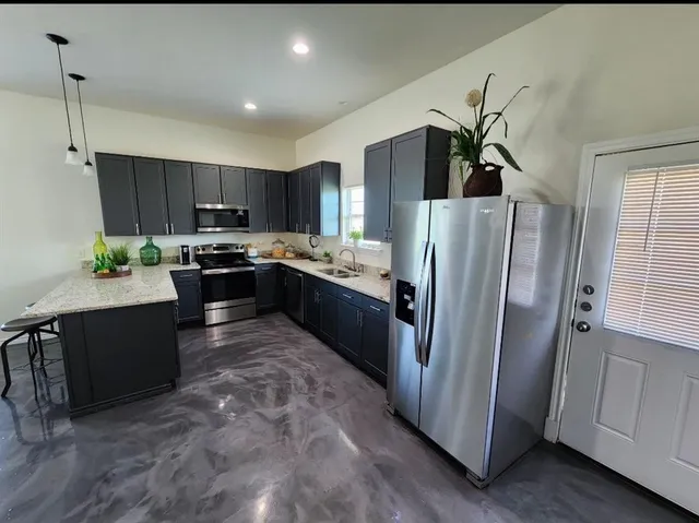 a kitchen with stainless steel appliances granite countertop a refrigerator a stove a sink a microwave a dining table and chairs