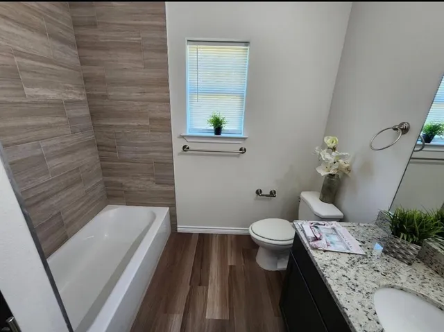 a bathroom with a granite countertop toilet and a sink