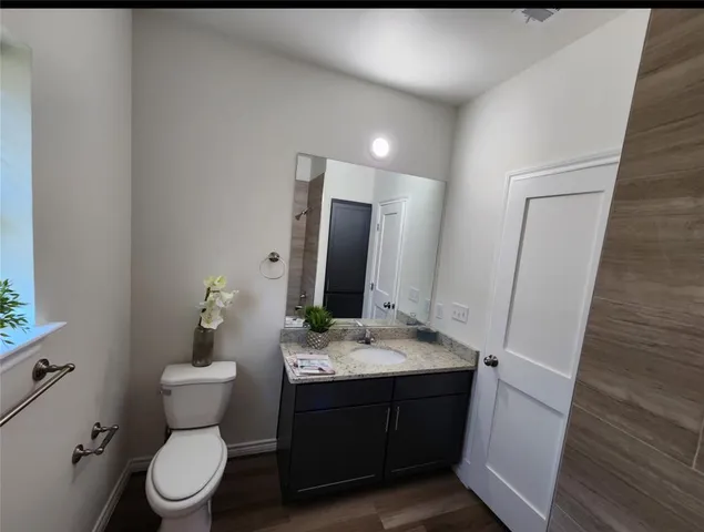 a bathroom with a sink vanity granite toilet and a mirror