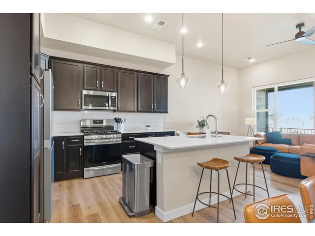 a kitchen with kitchen island granite countertop a stove top oven a sink dishwasher a dining table and chairs with wooden floor