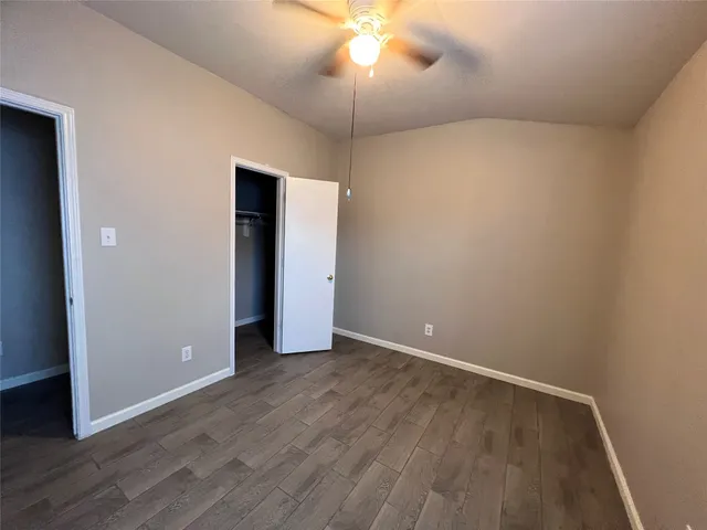 an empty room with wooden floor and chandelier fan