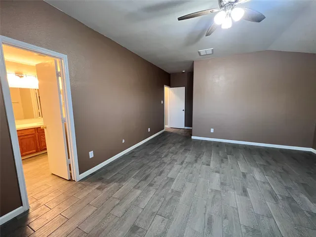an empty room with chandelier fan and windows