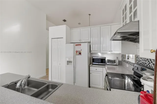 a kitchen with white cabinets and stainless steel appliances
