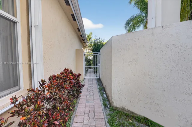 a view of a sign board with flower plants and large trees