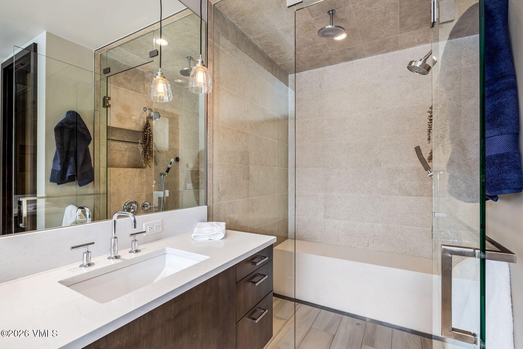 2440 Chamonix Lane Vail, CO 81657 - Photo 19 of 36 a bathroom with a bathtub shower sink vanity and a mirror